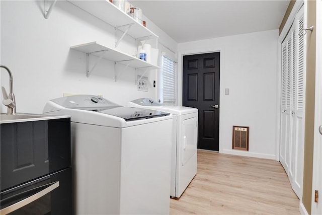 laundry area featuring sink, independent washer and dryer, and light wood-type flooring