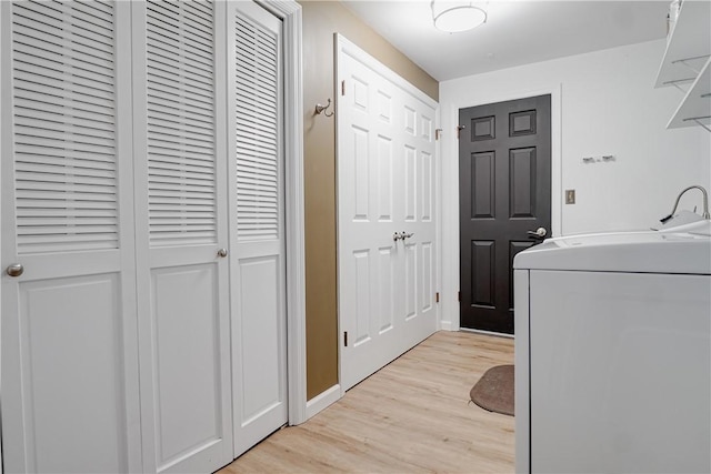 clothes washing area with washer / dryer and light hardwood / wood-style floors