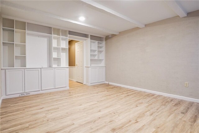 empty room featuring beamed ceiling and light hardwood / wood-style flooring