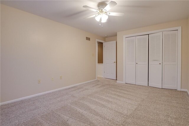 unfurnished bedroom featuring light carpet, a closet, and ceiling fan