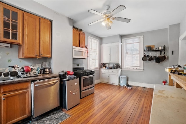 kitchen with sink, stainless steel appliances, ceiling fan, and light wood-type flooring