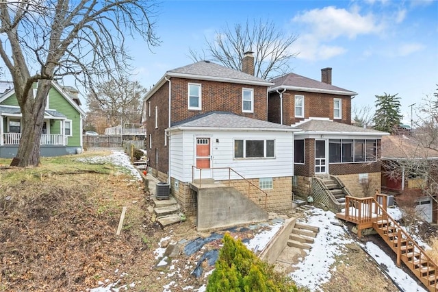 snow covered property with a sunroom and central air condition unit