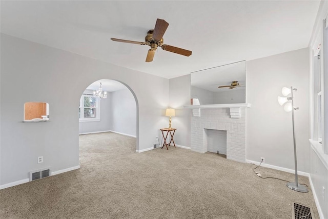 unfurnished living room featuring a brick fireplace, light carpet, and ceiling fan