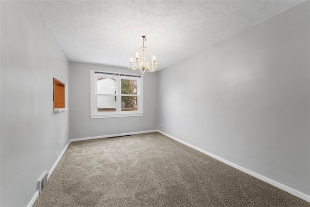 carpeted spare room with a chandelier and a textured ceiling