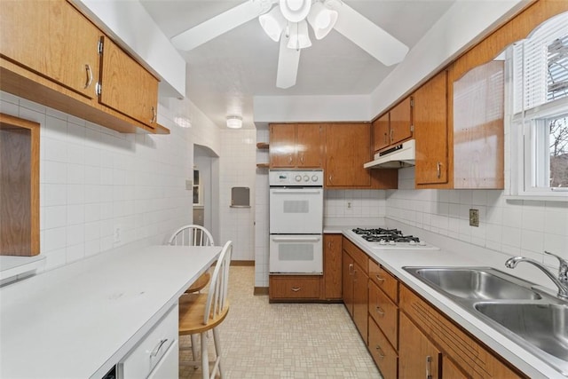 kitchen featuring sink, tile walls, backsplash, ceiling fan, and white appliances