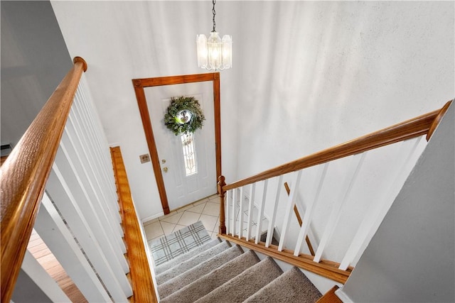 staircase featuring tile patterned flooring and an inviting chandelier