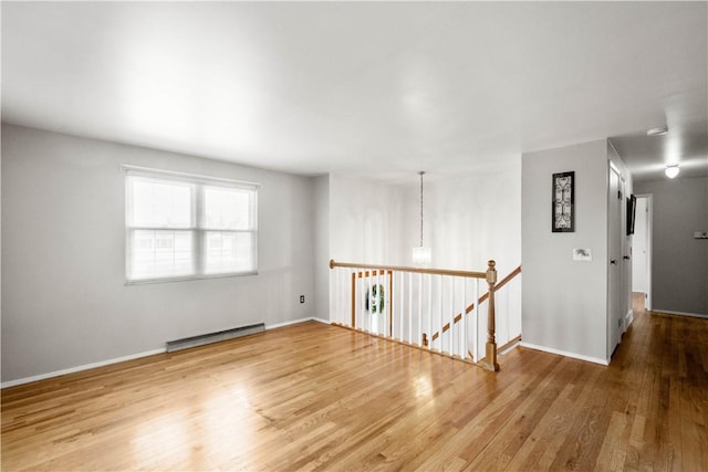 empty room with baseboard heating and hardwood / wood-style floors