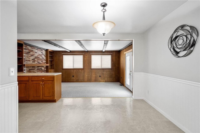 interior space featuring hanging light fixtures, built in features, beamed ceiling, and wood walls