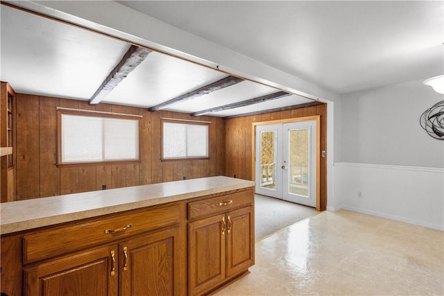 kitchen featuring french doors, wood walls, and beamed ceiling