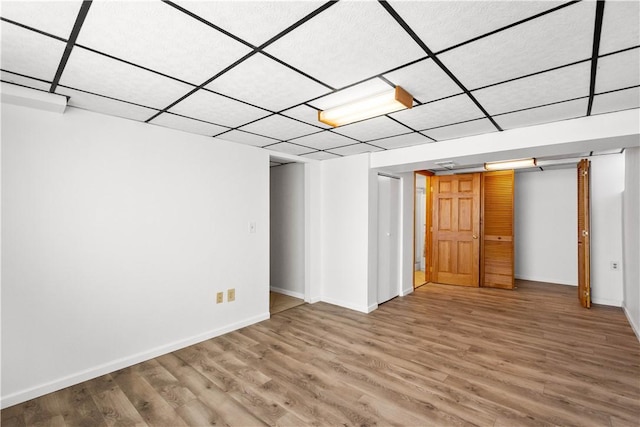 basement with a paneled ceiling and wood-type flooring