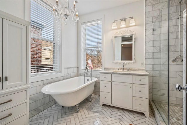 bathroom with independent shower and bath, vanity, tile walls, and an inviting chandelier