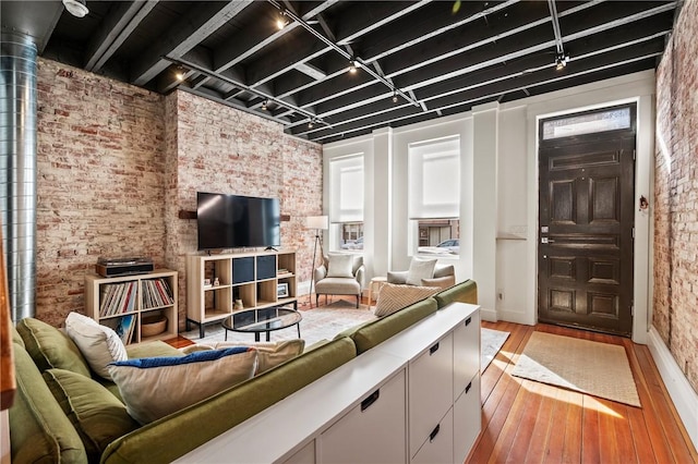 living room featuring brick wall and light hardwood / wood-style floors