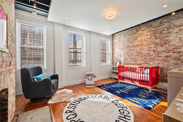 bedroom with brick wall and hardwood / wood-style floors