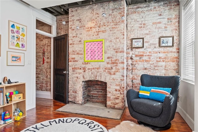 sitting room featuring brick wall and dark hardwood / wood-style flooring