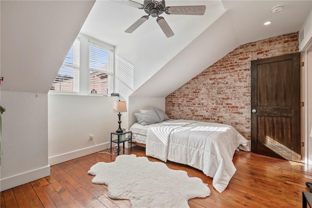 bedroom with brick wall, hardwood / wood-style floors, lofted ceiling, and ceiling fan