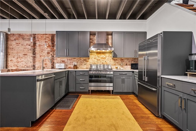 kitchen featuring appliances with stainless steel finishes, sink, gray cabinetry, and wall chimney exhaust hood