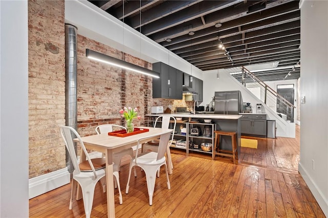 dining area with brick wall, sink, and light wood-type flooring