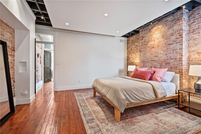 bedroom featuring brick wall and hardwood / wood-style floors