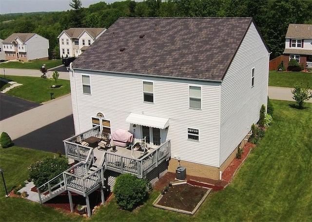 back of house featuring central AC unit, a deck, and a lawn