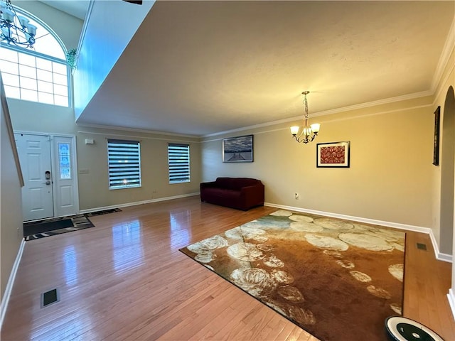 entryway featuring ornamental molding, a chandelier, hardwood / wood-style floors, and a high ceiling