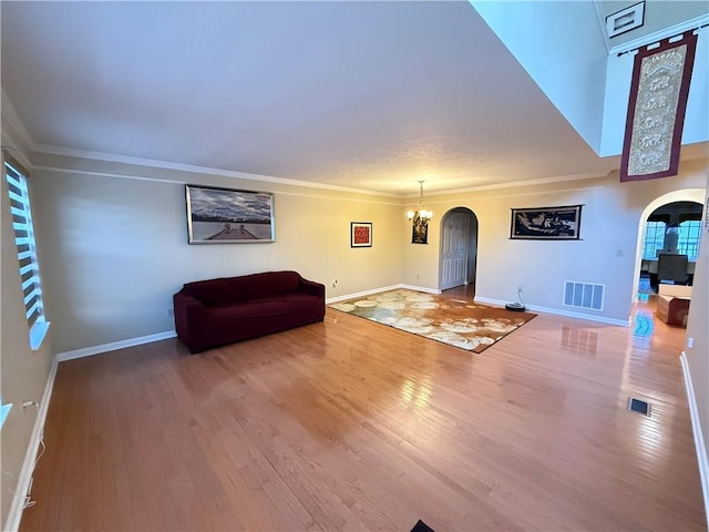 unfurnished living room with wood-type flooring, ornamental molding, and a chandelier