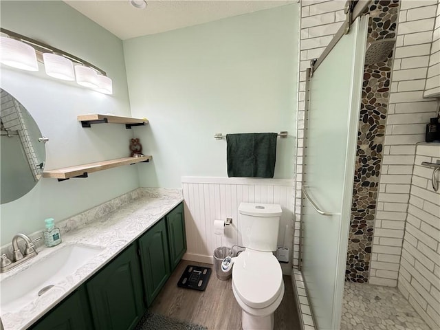 bathroom featuring hardwood / wood-style flooring, vanity, toilet, and a tile shower