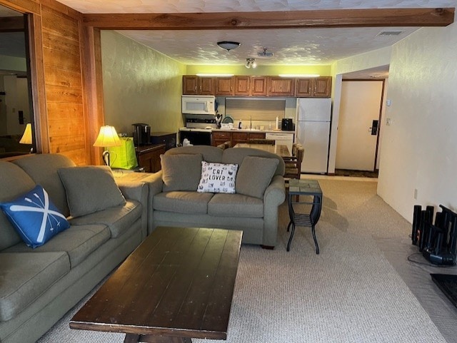 carpeted living room featuring beam ceiling and sink