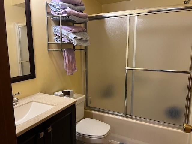 full bathroom with toilet, vanity, and bath / shower combo with glass door