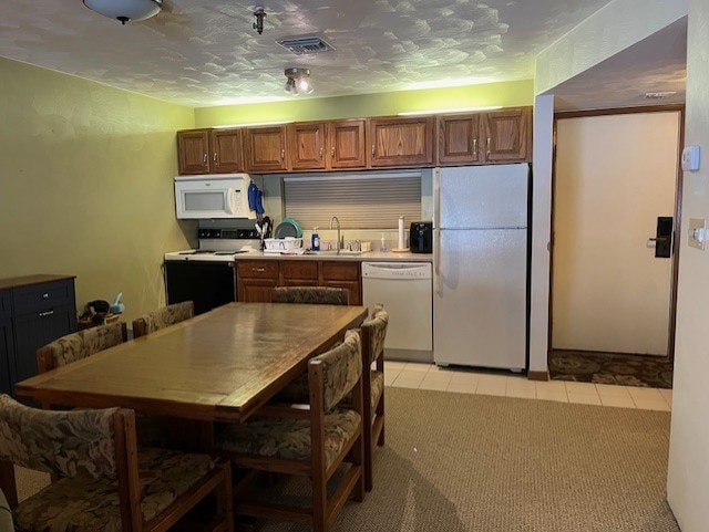 kitchen featuring sink, light colored carpet, a textured ceiling, and white appliances