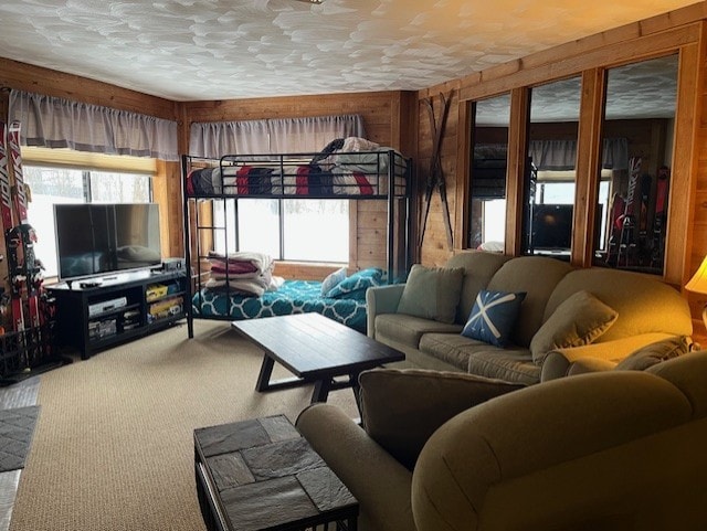 living room featuring carpet, a healthy amount of sunlight, a textured ceiling, and wooden walls