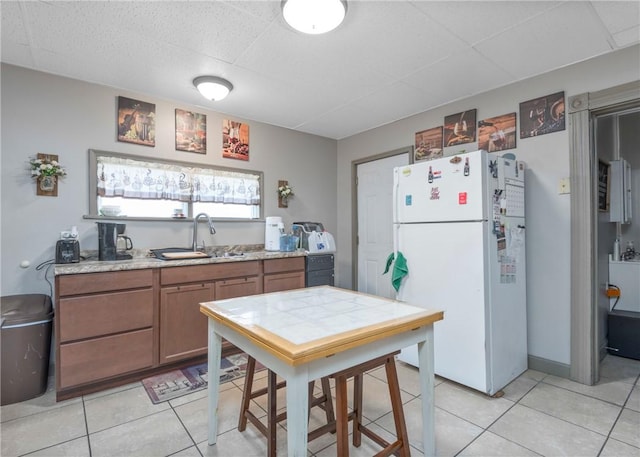 kitchen featuring white refrigerator, sink, and light tile patterned floors