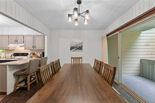 carpeted dining area with a chandelier