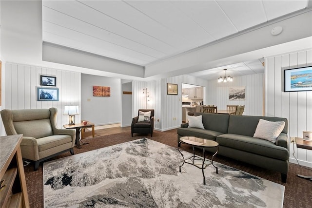 living room with an inviting chandelier and wood walls