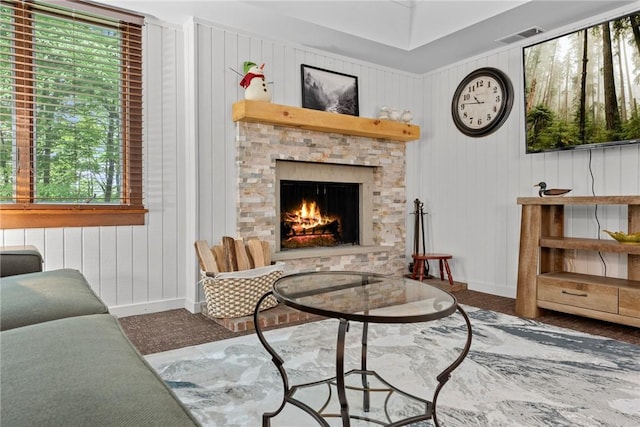 living area with a stone fireplace and wood walls