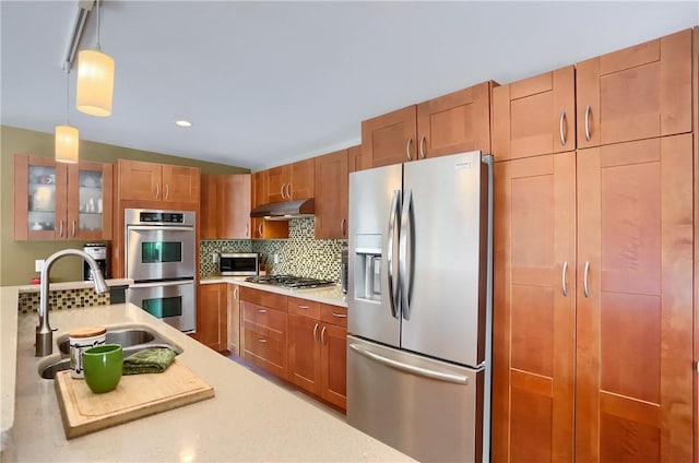 kitchen with stainless steel appliances, sink, decorative backsplash, and decorative light fixtures