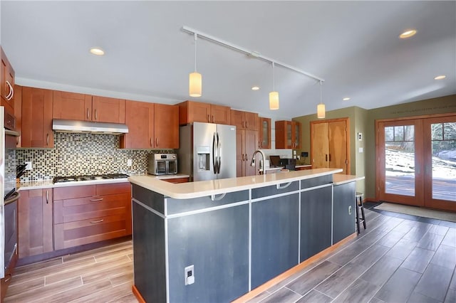 kitchen with tasteful backsplash, appliances with stainless steel finishes, a kitchen island with sink, and pendant lighting