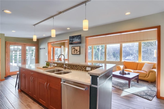 kitchen featuring french doors, sink, hanging light fixtures, stainless steel dishwasher, and a kitchen island with sink