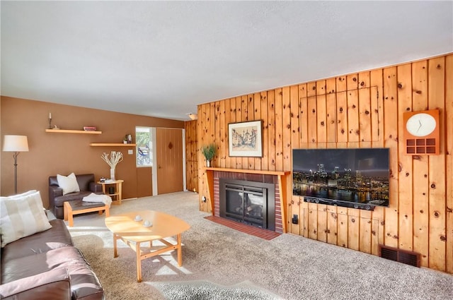 living room featuring carpet floors, a fireplace, and wood walls