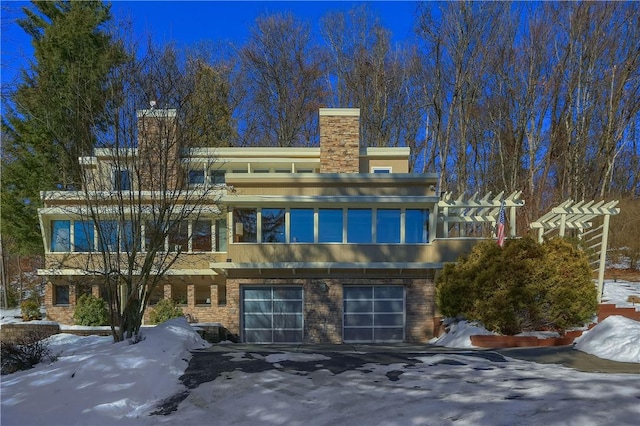 snow covered back of property with a garage