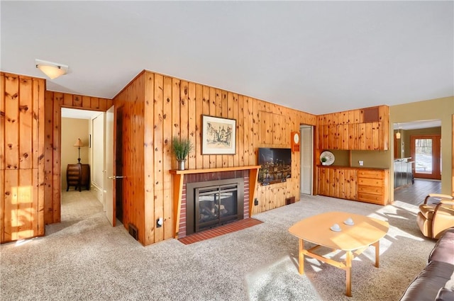 carpeted living room with a fireplace and wood walls