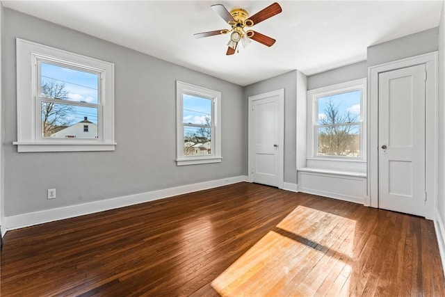 unfurnished bedroom with ceiling fan, dark hardwood / wood-style flooring, and multiple windows