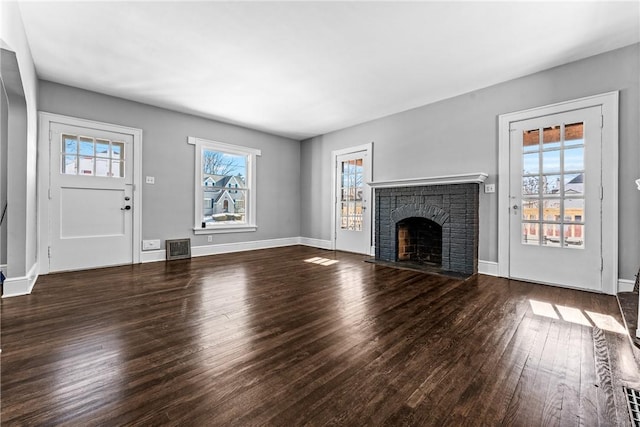 unfurnished living room featuring dark hardwood / wood-style flooring and a brick fireplace