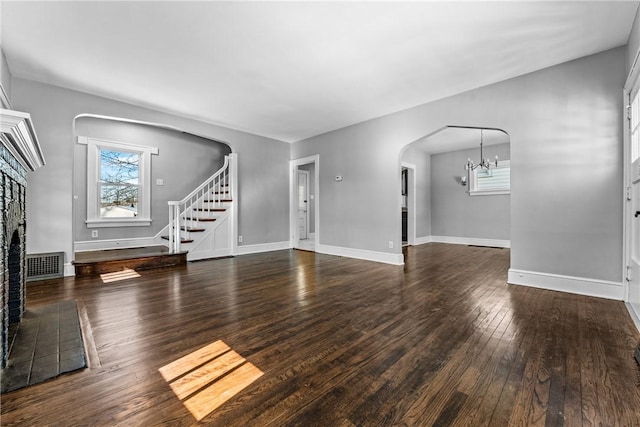 unfurnished living room with dark wood-type flooring and a notable chandelier