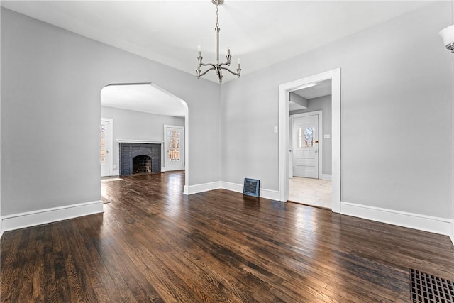 unfurnished living room with hardwood / wood-style flooring, a notable chandelier, and a fireplace