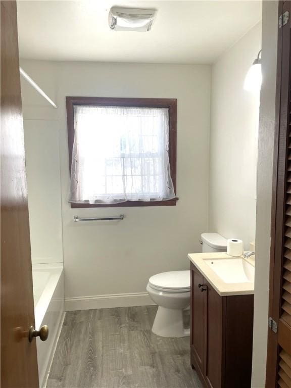 full bathroom with wood-type flooring, bathtub / shower combination, vanity, and toilet