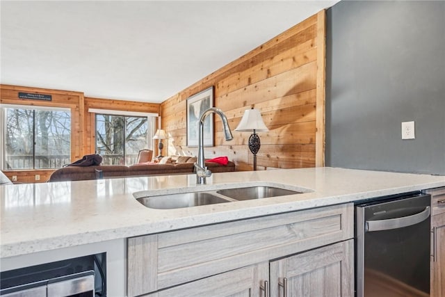 kitchen with sink, dishwasher, wine cooler, light brown cabinetry, and wood walls