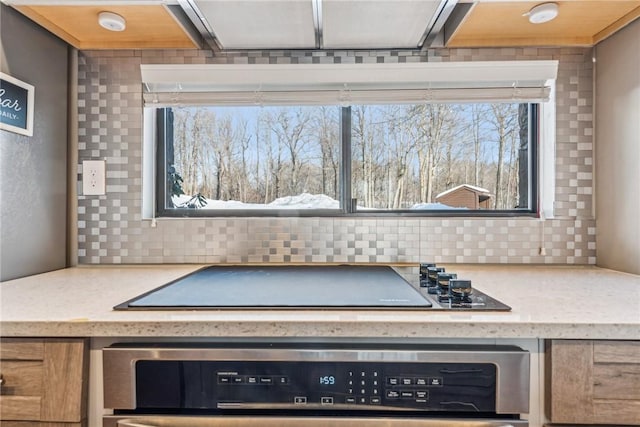 details featuring light stone counters, black electric stovetop, decorative backsplash, and oven