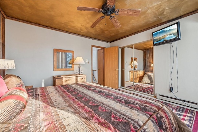 bedroom with ceiling fan, baseboard heating, and a closet