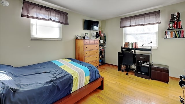 bedroom with multiple windows, vaulted ceiling, and light wood-type flooring