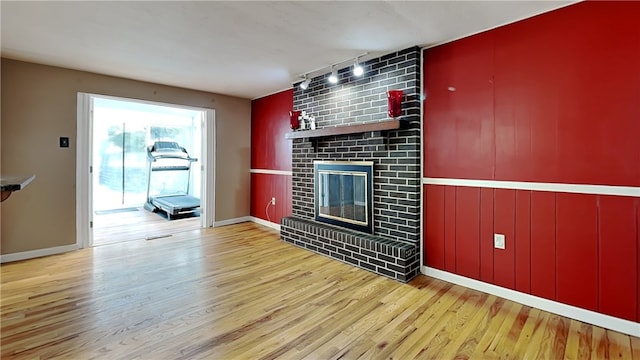 unfurnished living room with a fireplace, light hardwood / wood-style floors, and rail lighting